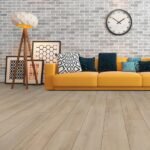 Modern living room with light oak flooring, a yellow sofa, and a grey brick wall.
